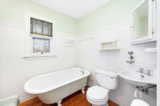 bathroom with ornamental molding, a soaking tub, toilet, and wood finished floors