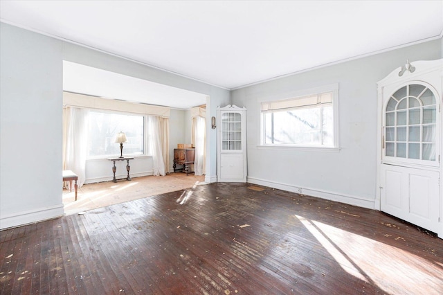 unfurnished living room featuring a healthy amount of sunlight, baseboards, hardwood / wood-style floors, and ornamental molding