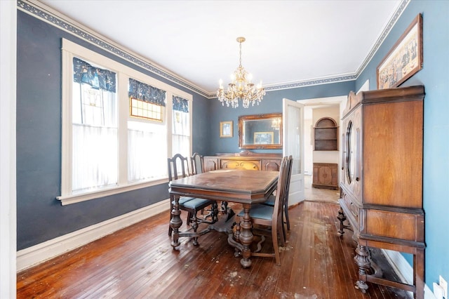 dining space featuring hardwood / wood-style flooring, baseboards, ornamental molding, and a notable chandelier