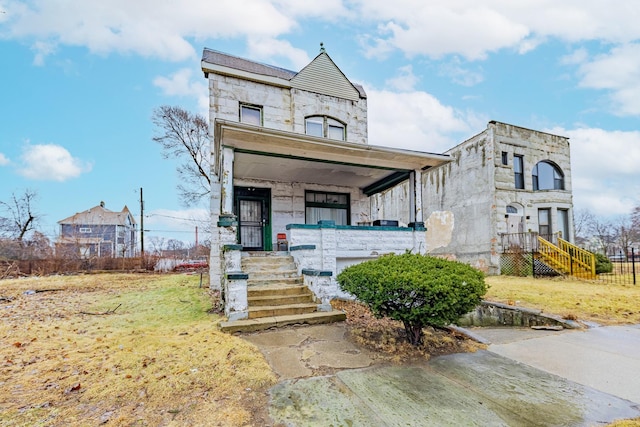 view of front facade with a front yard, stone siding, and covered porch