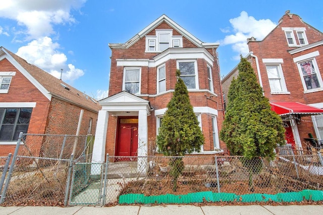 view of front of property with a fenced front yard, a gate, and brick siding