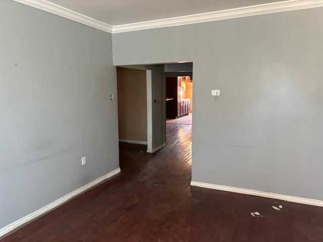 unfurnished room featuring ornamental molding, wood finished floors, and baseboards