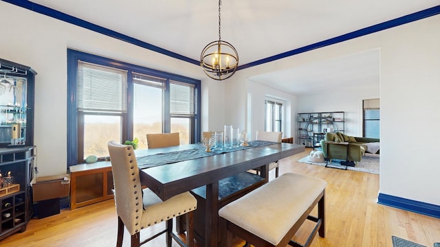 dining space with crown molding, baseboards, a notable chandelier, and light wood finished floors