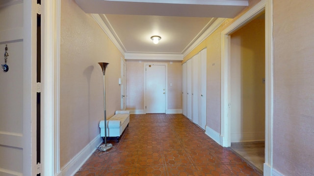 hall featuring dark tile patterned flooring, crown molding, and baseboards