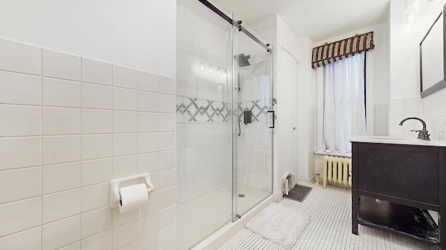 full bath with radiator heating unit, tile patterned flooring, vanity, and a stall shower