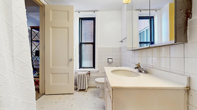 bathroom featuring toilet, radiator heating unit, vanity, and tile walls