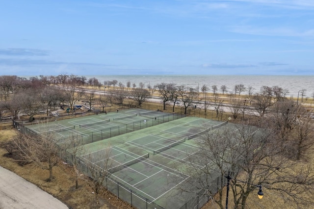 surrounding community with a tennis court, a water view, and fence