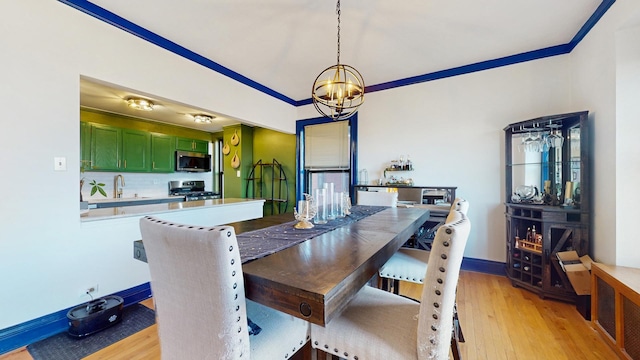 dining area featuring ornamental molding, a notable chandelier, light wood-style flooring, and baseboards