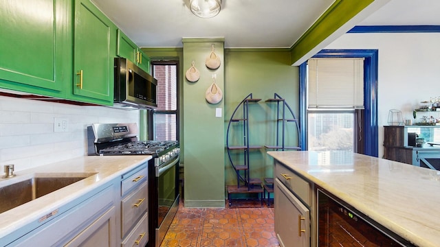 kitchen with beverage cooler, decorative backsplash, appliances with stainless steel finishes, dark tile patterned floors, and green cabinetry