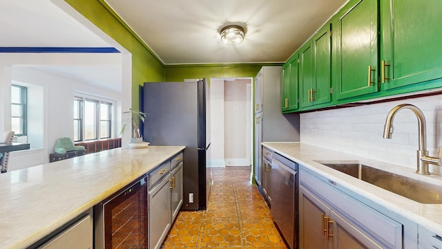 kitchen featuring wine cooler, light countertops, green cabinets, appliances with stainless steel finishes, and a sink