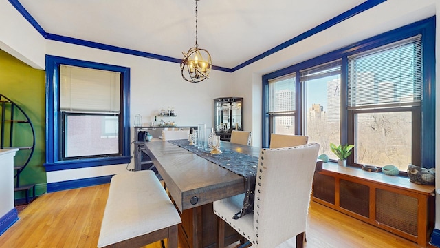 dining space featuring a notable chandelier, crown molding, baseboards, and wood finished floors