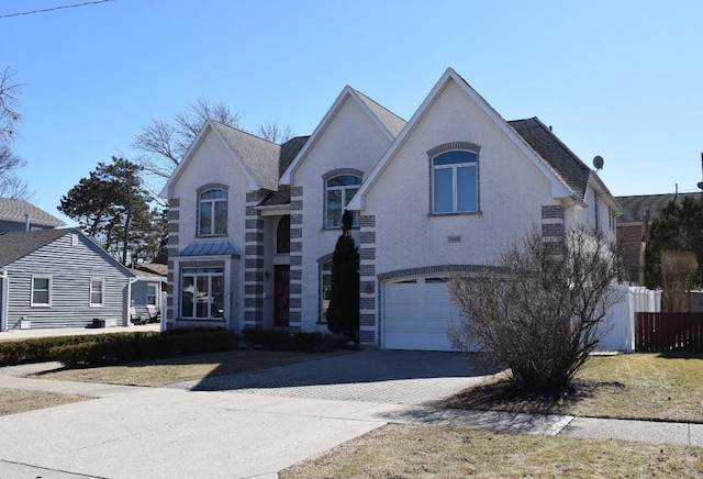 french country inspired facade featuring a garage, aphalt driveway, and brick siding