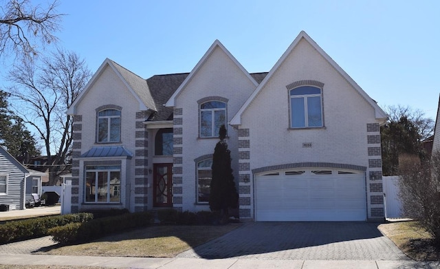 french provincial home featuring an attached garage, aphalt driveway, and brick siding