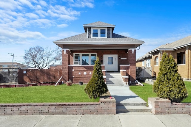 view of front of house with a front yard, brick siding, and fence