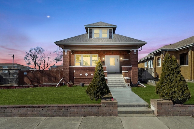 bungalow-style home with a porch, brick siding, fence, and a front lawn