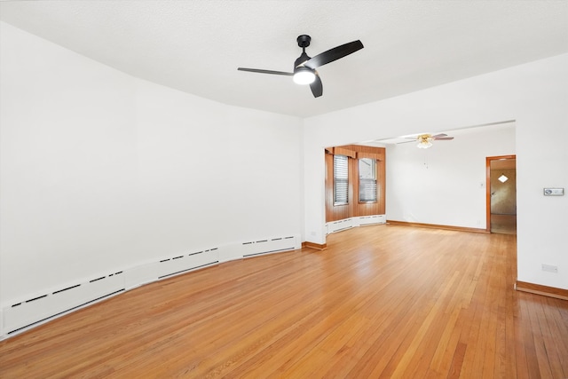 empty room featuring light wood finished floors, a baseboard radiator, baseboards, and a ceiling fan