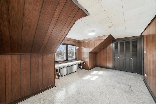 bonus room featuring light floors, radiator heating unit, and wooden walls