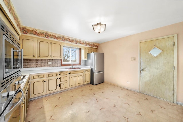 kitchen featuring stainless steel appliances, a sink, light countertops, and baseboards