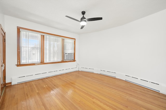 spare room with a ceiling fan, wood-type flooring, and baseboard heating