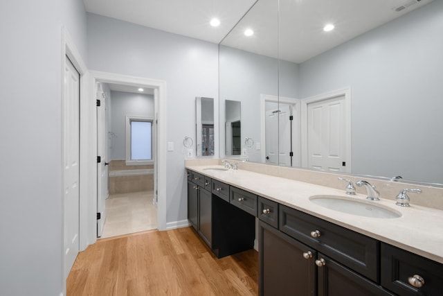 bathroom with double vanity, visible vents, a sink, and wood finished floors