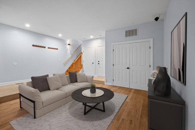 living area with baseboards, visible vents, stairway, light wood-type flooring, and recessed lighting