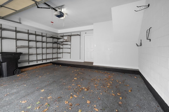 garage featuring concrete block wall and a garage door opener