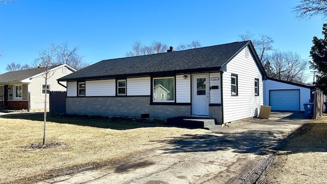 view of front of property with brick siding, a detached garage, roof with shingles, an outdoor structure, and driveway