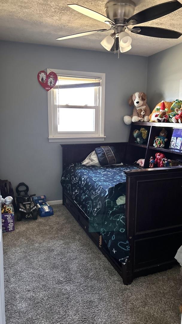 carpeted bedroom with ceiling fan and a textured ceiling