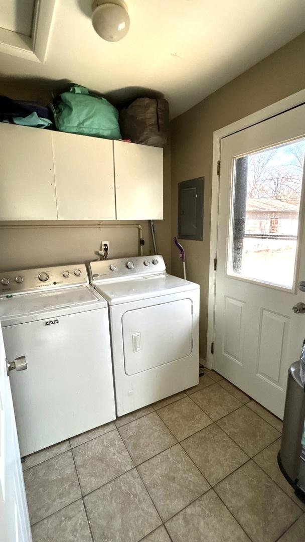 washroom with electric panel, cabinet space, washing machine and clothes dryer, and light tile patterned flooring