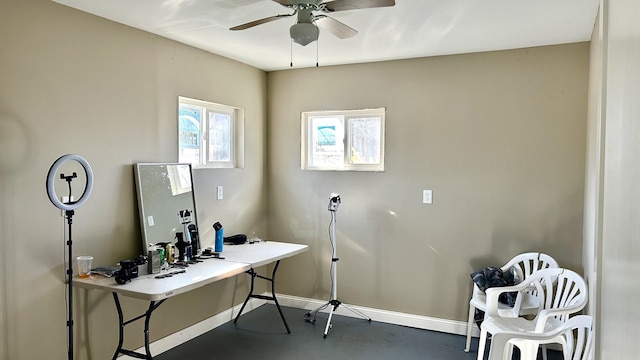 home office featuring finished concrete floors, baseboards, and a ceiling fan