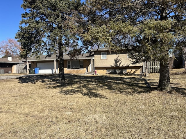 tri-level home featuring central air condition unit, a front lawn, an attached garage, and fence