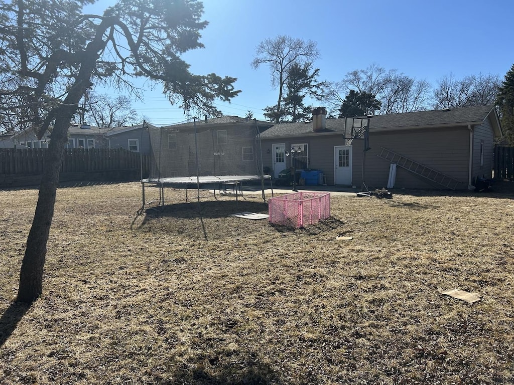 view of yard featuring a trampoline and fence