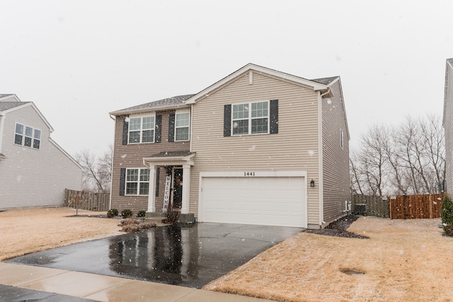 traditional-style house featuring central AC unit, aphalt driveway, an attached garage, and fence