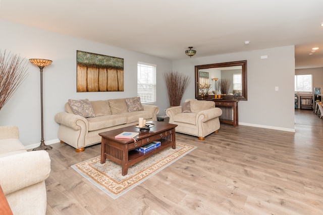 living room featuring baseboards, a wealth of natural light, and light wood-style floors