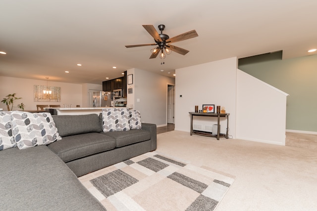 living area featuring light carpet, ceiling fan with notable chandelier, and recessed lighting