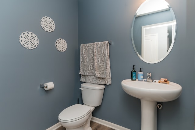 bathroom with baseboards, toilet, and wood finished floors