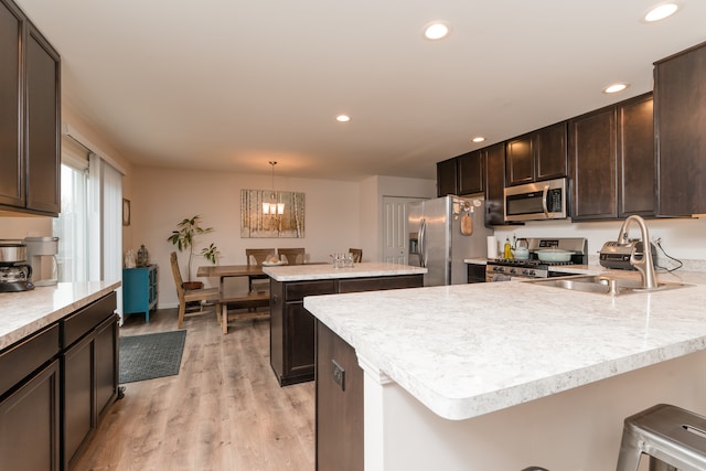 kitchen with light wood-style flooring, a sink, dark brown cabinets, appliances with stainless steel finishes, and light countertops