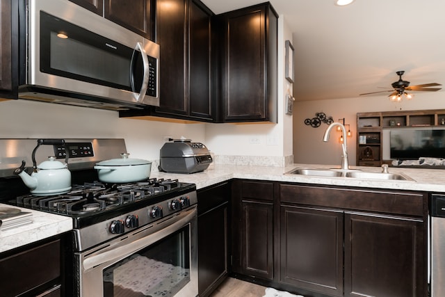 kitchen with stainless steel appliances, light countertops, a sink, ceiling fan, and dark brown cabinets