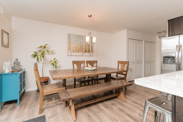 dining area with light wood-type flooring, baseboards, and a chandelier