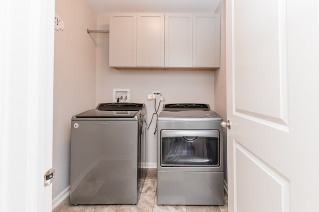 clothes washing area featuring cabinet space, baseboards, and washer and clothes dryer