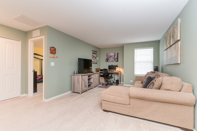 living area with baseboards, visible vents, and light colored carpet