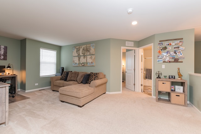 living room featuring light colored carpet, visible vents, and baseboards