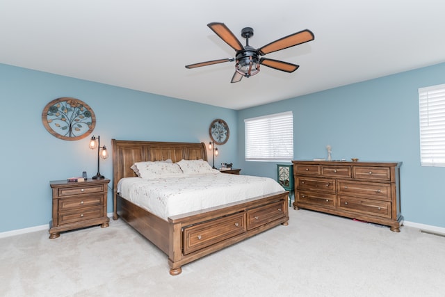 bedroom with ceiling fan, baseboards, and light colored carpet