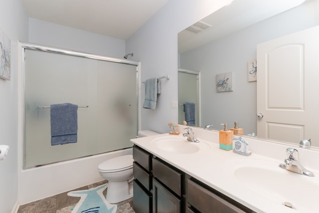 full bath with bath / shower combo with glass door, double vanity, a sink, and toilet