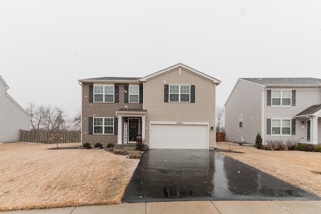 traditional home with aphalt driveway, an attached garage, and fence