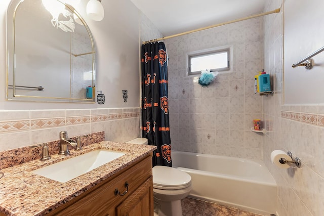 full bath featuring vanity, shower / bathtub combination with curtain, wainscoting, tile walls, and toilet