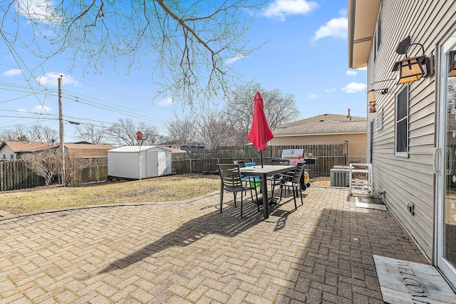 view of patio featuring a fenced backyard, an outbuilding, a storage shed, and outdoor dining space