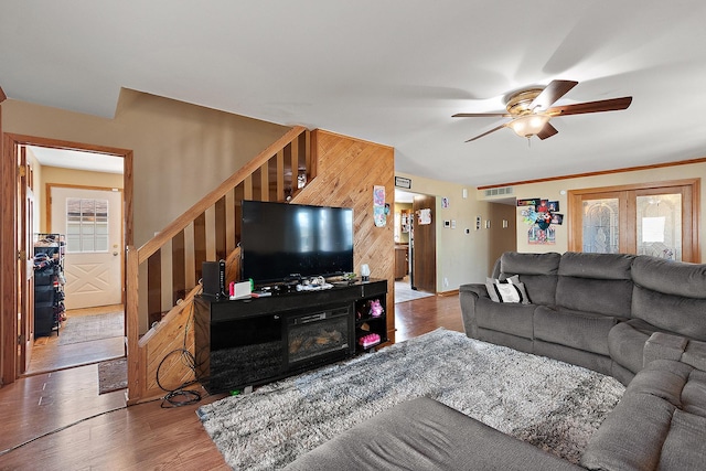 living area with stairs, a ceiling fan, and wood finished floors