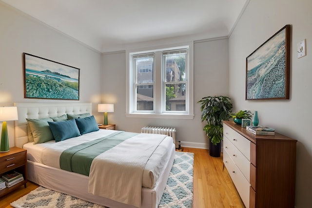 bedroom with light wood-type flooring, baseboards, and radiator heating unit