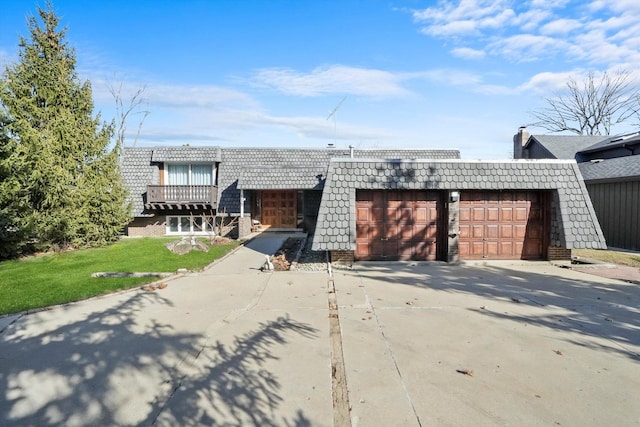 view of front of house featuring concrete driveway, mansard roof, an attached garage, and a front yard